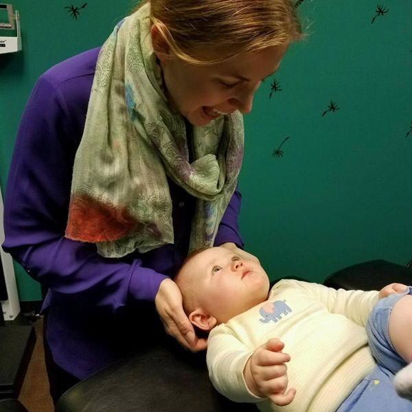 chiropractor looking down at baby